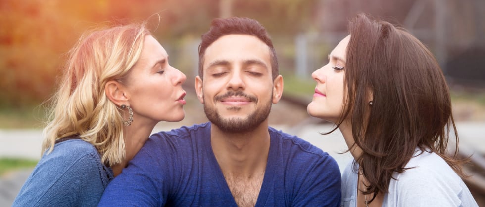 Man in the centre, woman on the left and woman on the right kissing the man as a symbol for tips for a polyamorous relationship