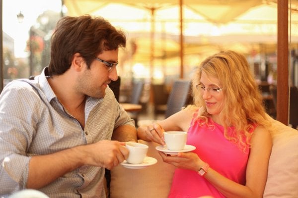 Man and woman sitting on bench looking at each other as symbol for first date tips