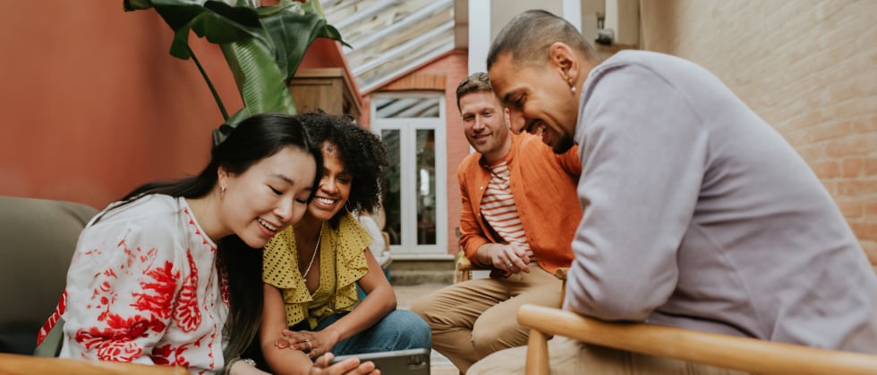 a group of people sitting and looking at a phone together