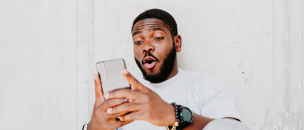 A man looking at his phone, finding a girlfriend online.