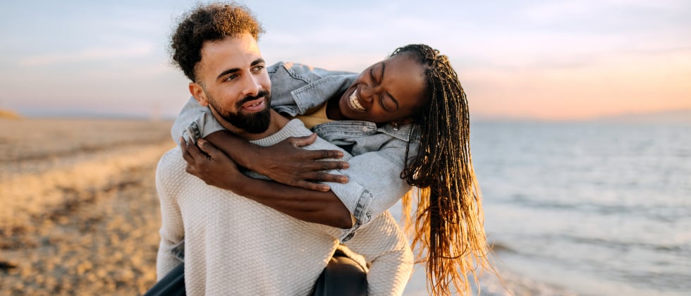 An older woman and a younger man having fun at the beach.